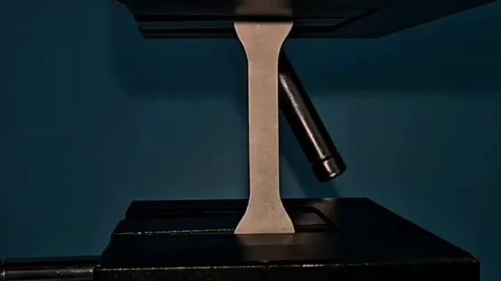Actual hybrid cellulose paper tensile coupon held between testing-machine grips in the authors’ laboratory video