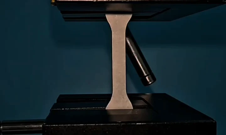Actual hybrid cellulose paper tensile coupon held between testing-machine grips in the authors’ laboratory video